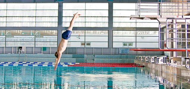 Springer springt vom Sprungturm in der 50-Meter-Schwimmhalle