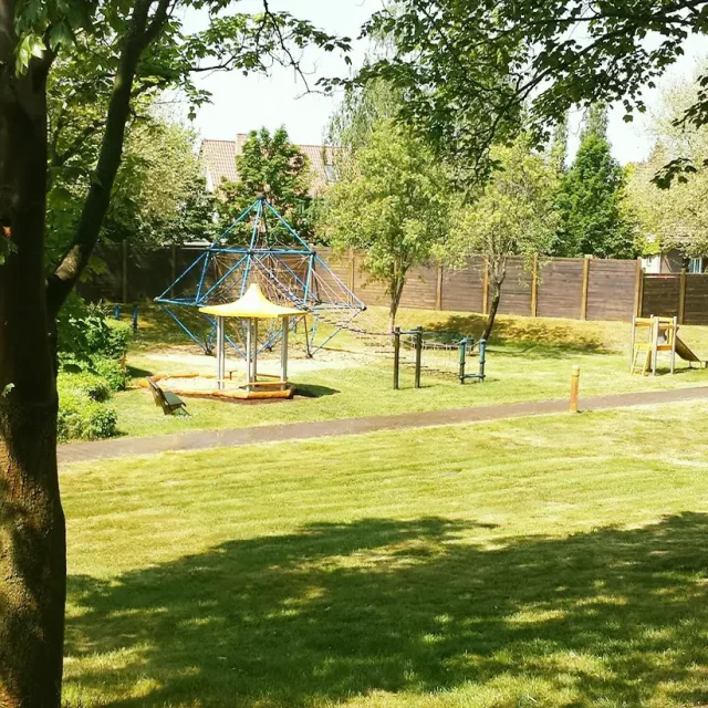 Spielplatz mit Klettergerüst, Rutsche, Buddelkasten und Tierwippen