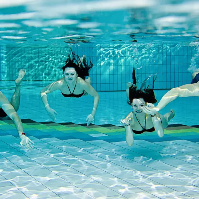 Unterwasseraufnahme von vier tauchenden Jugendlichen