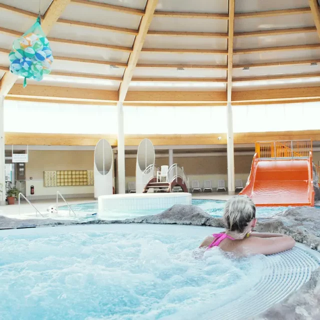 Frau im Whirlpool mit Blick auf Wasserrutschen, Gegenstromkanal und Sprudeldüsen