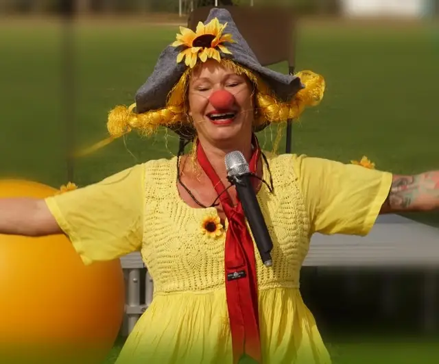 Frau als Clown verkleidet mit einer Sonnenblume am Hut