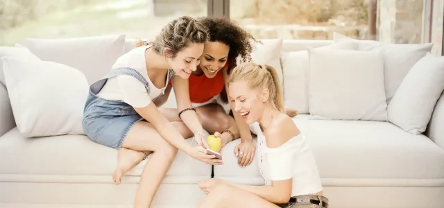 Drei Mädchen auf der Couch mit einem Handy